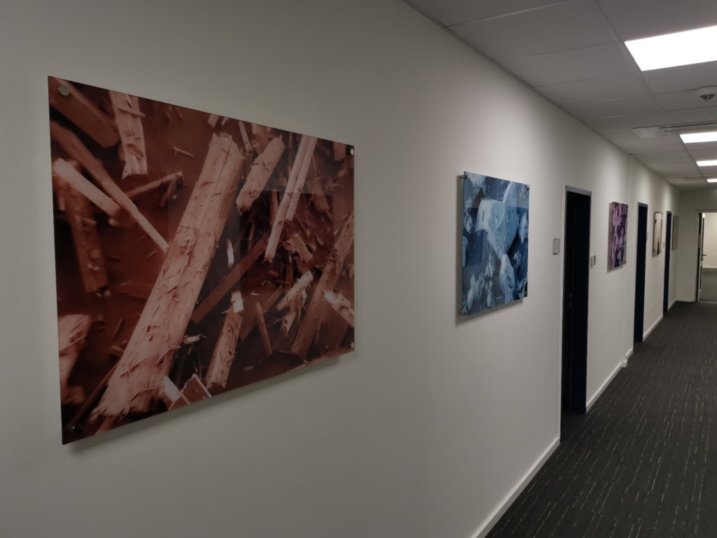 Acrylic glass pictures mounted on stand-offs in a TAD Pharma corridor; the image is viewed through the acrylic glass.