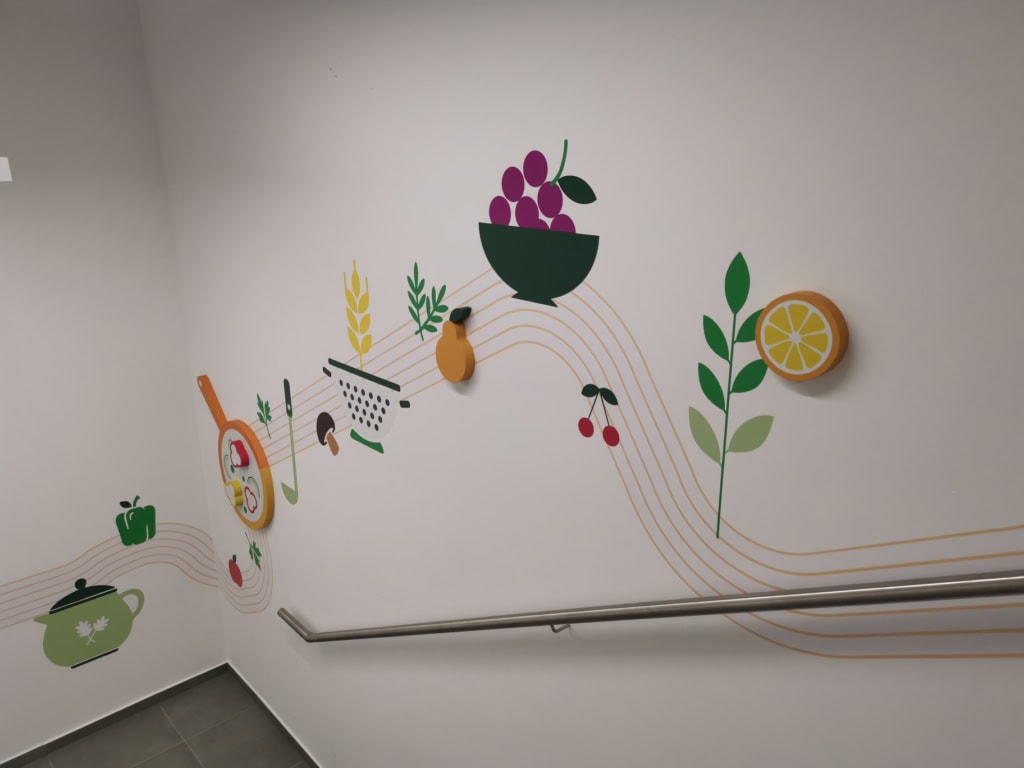 Stenske grafike in 3D elementi ob stopnišču v prostorih Krke.